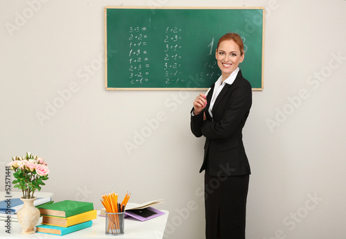 Photo: Portrait of teacher woman near chalkboard in classroom Portrait of teacher woman near chalkboard in classroom