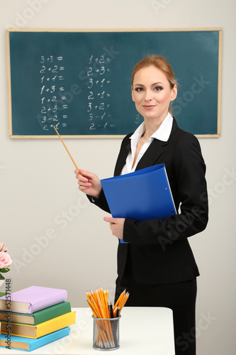 Photo: Portrait of teacher woman near chalkboard in classroom Portrait of teacher woman near chalkboard in classroom
