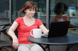 Woman using laptop in a outdoor cafe