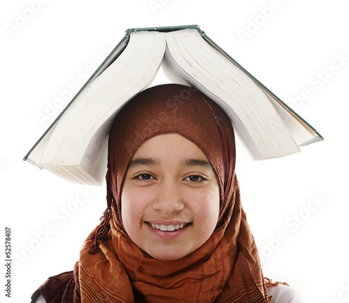 Photo: Female Arabic student balancing big book on head Female Arabic student balancing big book on head