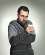 Cold, sick man holding a cup of tea in hands