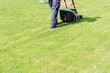 Man moves with lawnmower & mows green grass