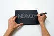 two hand writing "nervous" on a black background