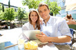 Couple connected on digital tablet in Santa Ana square