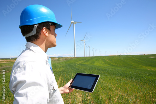 Photo: Businessman checking on wind turbine energy production Businessman checking on wind turbine energy production