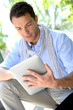 Photo: Handsome guy websurfing on internet with tablet Handsome guy websurfing on internet with tablet