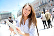 Cheerful girl with tablet walking in city