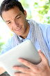 Handsome guy websurfing on internet with tablet
