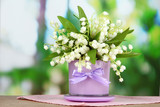 Beautiful lily of the valley in vase on nature background