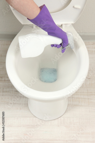 Photo: Woman hand with spray bottle cleaning a toilet bowl in a Woman hand with spray bottle cleaning a toilet bowl in a