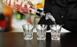 Barmen hand with bottle  pouring beverage into glasses,