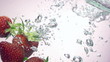 fresh strawberry dropped into water with splash on backgrounds
