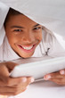 Boy Using Digital Tablet Under Duvet