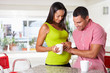 Pregnant Woman And Husband Having Breakfast In Kitchen