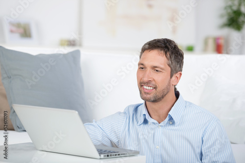 Photo: lächelnder mann mit laptop zu hause lächelnder mann mit laptop zu hause