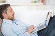 mann liegt mit laptop auf dem sofa