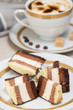 Slices of chocolate cake and coffee with cream on background