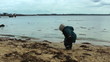 Child throwing sea shells in water, polluted beach
