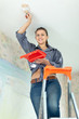 Woman paints ceiling with brush