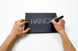 two hand writing "hands" on a black background