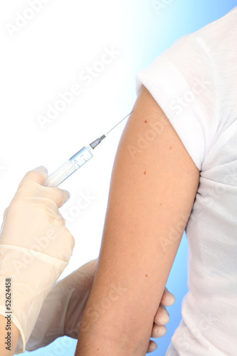 Photo: Doctor holding syringe with a vaccine in the patient shoulder, Doctor holding syringe with a vaccine in the patient shoulder,