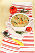 Nourishing soup in pink pan on wooden table close-up