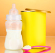 Bottle with milk and food for babies on beige background