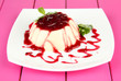 Panna Cotta with raspberry sauce, on color wooden background
