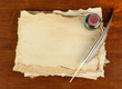 Old paper, ink and feather on wooden background