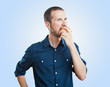 Cheerful beautiful man eating apple, isolated over white backgro