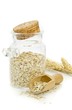 A jar of oatmeal flakes and wheat on a white background