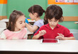 Boy Using Digital Tablet With Friend At Desk