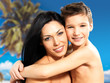  happy smiling mother hugs son at tropical beach