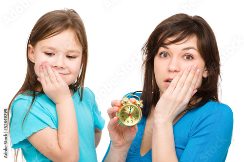 Photo: Little girl and her mother are anxious about time Little girl and her mother are anxious about time