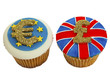 Two iced cupcakes decorated with Euro and Sterling signs.