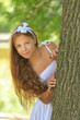 frightened teenage peeping from behind tree