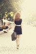 Photo: Young woman with suitcase walking on the city street Young woman with suitcase walking on the city street
