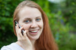 Foto: Junge Frau telefoniert im Grünen und lacht Junge Frau telefoniert im Grünen und lacht