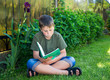 Photo: boy with a book on the grass boy with a book on the grass