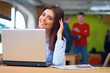 Happy young busineswoman sitting in the office with laptop