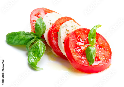 Photo: Caprese Salad. Tomato and Mozzarella slices with basil leaves Caprese Salad. Tomato and Mozzarella slices with basil leaves