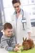 Smiling boy feeding rabbit at pets' clinic