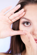 Young woman putting contact lens in her eye close up