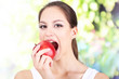 Young woman with apple on bright background