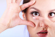 Young woman putting contact lens in her eye close up