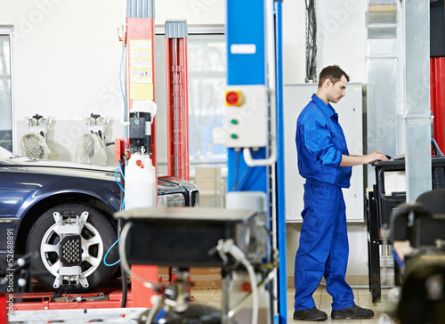 Photo: car mechanic at wheel alignment with computer car mechanic at wheel alignment with computer