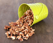 Quadro Overturned bucket with nuts on wooden background