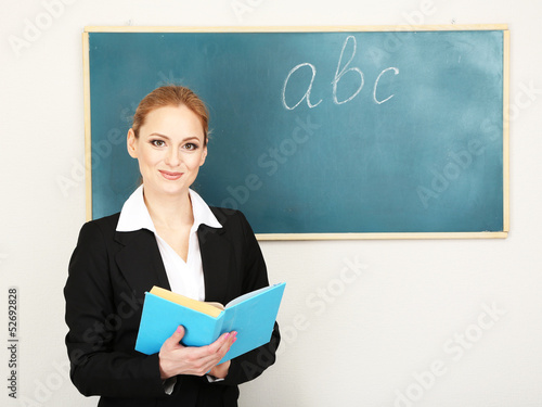 Photo: Portrait of teacher woman near chalkboard in classroom Portrait of teacher woman near chalkboard in classroom