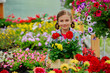 Lovely girl holding flowers in garden center.
