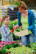 Mother with daughter shopping plants and flowers in garden cente